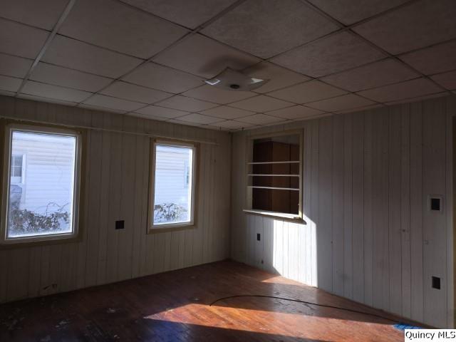 spare room with dark hardwood / wood-style floors, a paneled ceiling, and wood walls