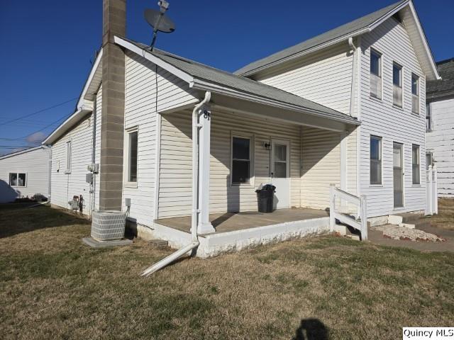 view of side of home featuring a porch, a yard, and central AC unit