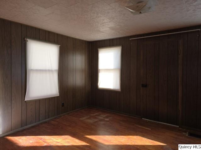 spare room with dark hardwood / wood-style floors and wood walls