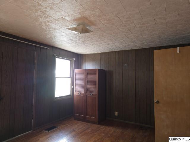 unfurnished bedroom featuring dark wood-type flooring and wood walls