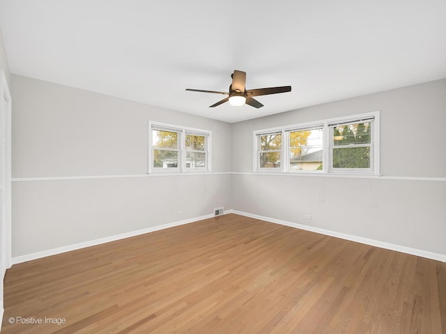 empty room featuring hardwood / wood-style floors, ceiling fan, and a healthy amount of sunlight