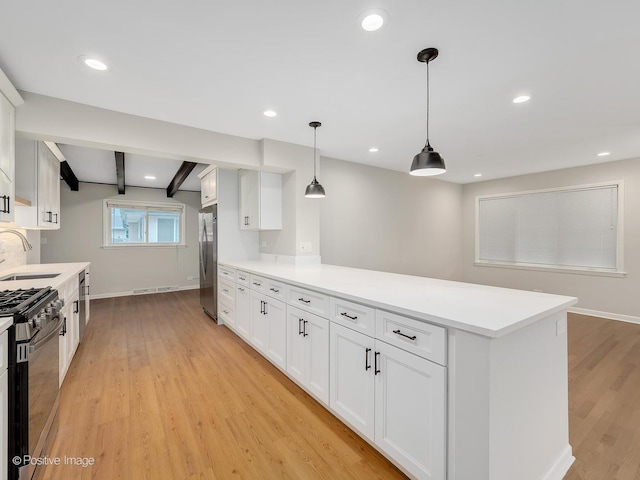 kitchen featuring white cabinets, appliances with stainless steel finishes, pendant lighting, and beamed ceiling