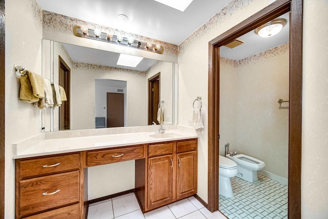 bathroom with tile patterned flooring, vanity, toilet, and a bidet