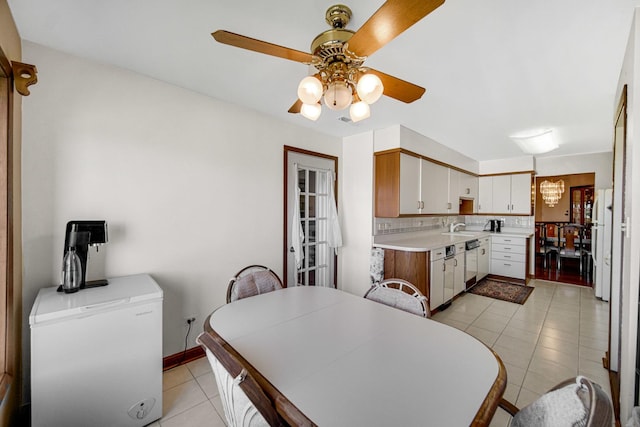 kitchen with sink, light tile patterned flooring, decorative backsplash, white cabinets, and ceiling fan with notable chandelier