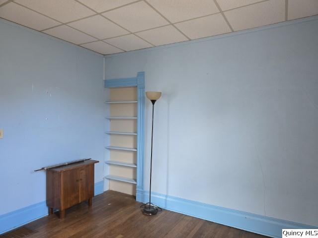 empty room featuring a paneled ceiling and dark hardwood / wood-style flooring