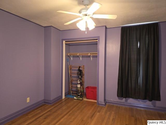 unfurnished bedroom featuring hardwood / wood-style floors, ceiling fan, and a closet