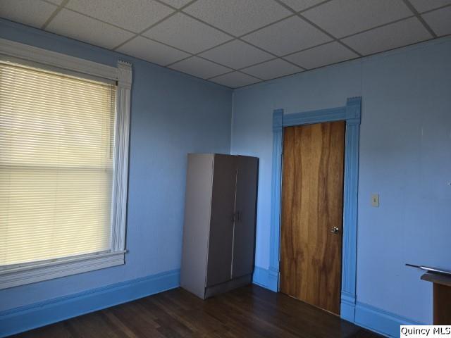 empty room with dark wood-type flooring and a paneled ceiling