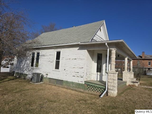 view of side of home featuring central AC unit and a lawn