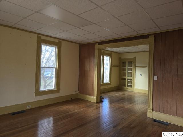 spare room featuring dark hardwood / wood-style flooring, a paneled ceiling, and wooden walls