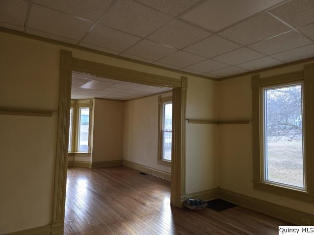 empty room with wood-type flooring and a paneled ceiling