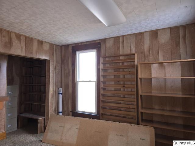 unfurnished bedroom with carpet flooring and wood walls