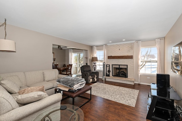 living room featuring dark hardwood / wood-style flooring, a brick fireplace, and ceiling fan