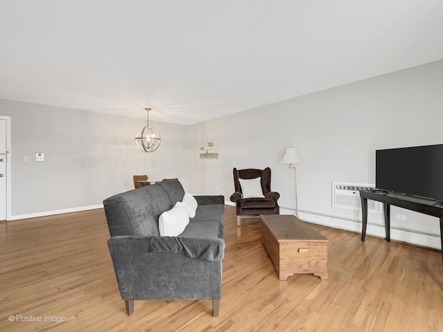 living room featuring baseboard heating, an AC wall unit, a chandelier, and light wood-type flooring