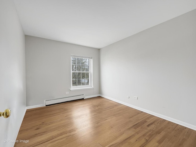 empty room featuring a baseboard radiator and light wood-type flooring