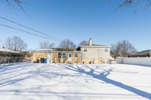 snow covered back of property with central AC