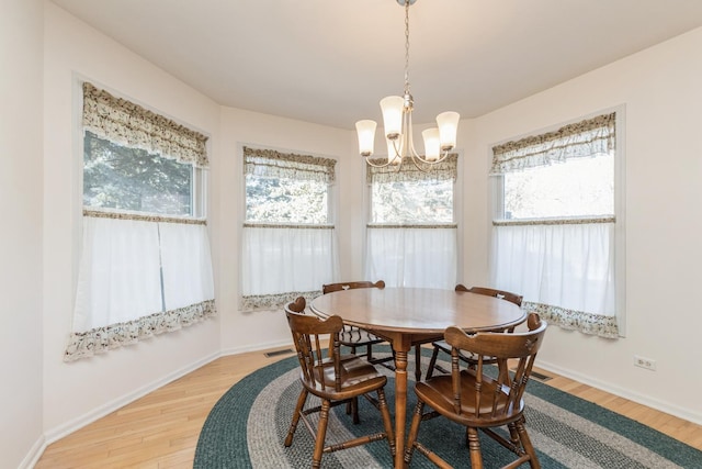 dining area with light hardwood / wood-style floors, plenty of natural light, and a chandelier