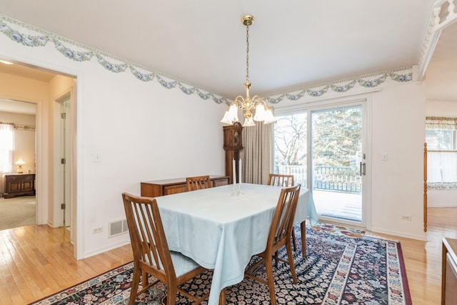 dining space featuring light wood-type flooring and a chandelier