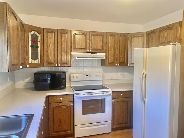 kitchen featuring light wood-type flooring, sink, backsplash, and white appliances