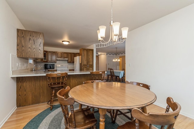 dining space featuring an inviting chandelier, light hardwood / wood-style flooring, and sink