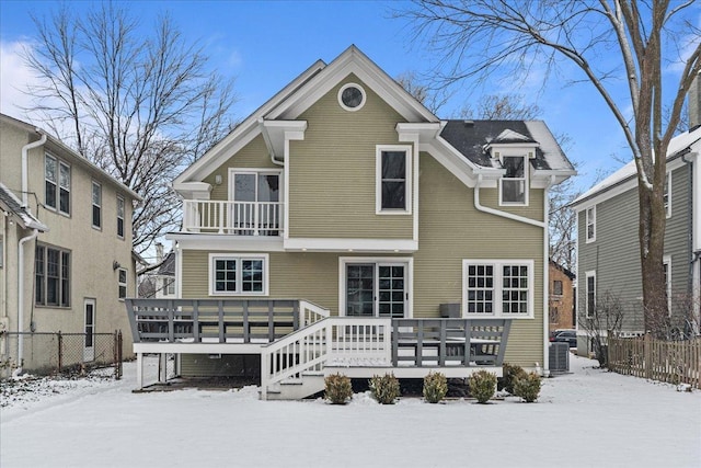 snow covered house with a balcony, central AC unit, and a wooden deck