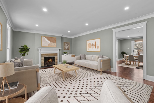 living room with plenty of natural light, a fireplace, crown molding, and hardwood / wood-style floors