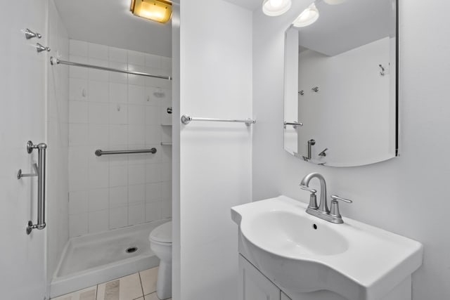 bathroom with vanity, tile patterned flooring, toilet, and tiled shower