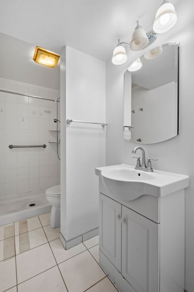 bathroom with vanity, a tile shower, tile patterned flooring, and toilet