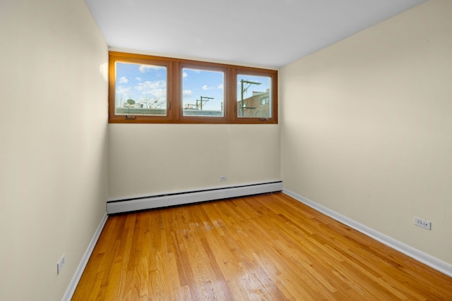 empty room with a baseboard heating unit and light hardwood / wood-style floors