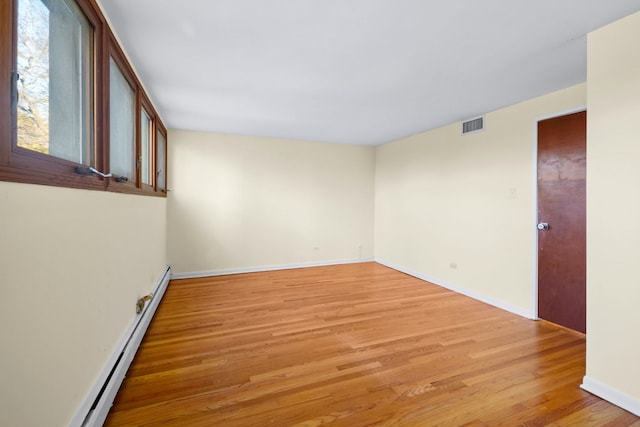 unfurnished room with light hardwood / wood-style floors and a baseboard heating unit