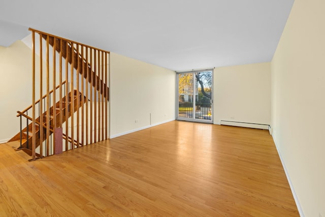 spare room featuring light hardwood / wood-style floors, expansive windows, and a baseboard heating unit