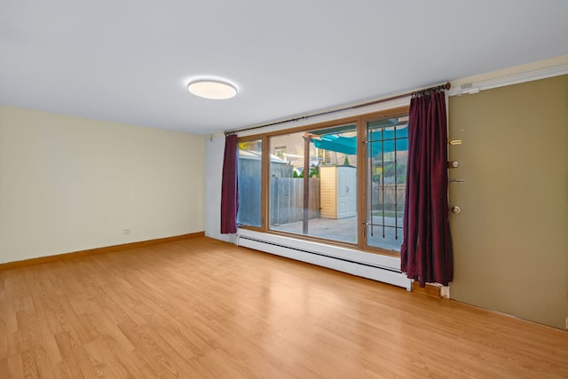 empty room featuring a baseboard heating unit and light wood-type flooring