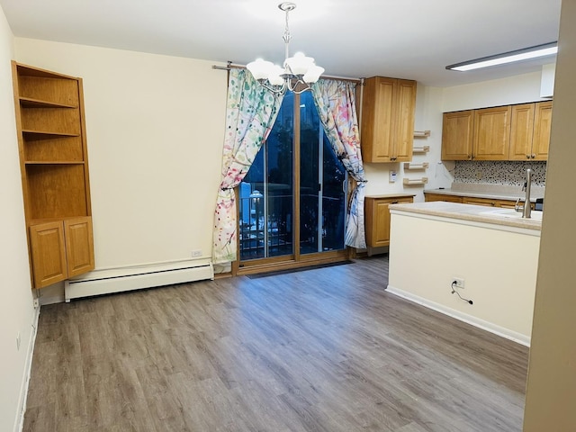 kitchen with a baseboard radiator, decorative backsplash, hardwood / wood-style floors, and pendant lighting