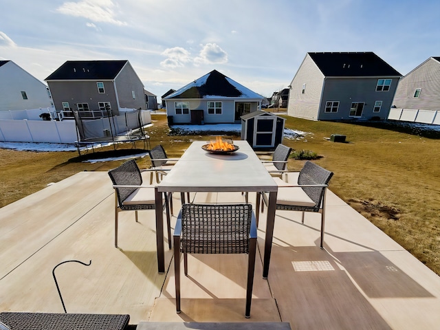 view of patio with an outdoor fire pit, a trampoline, and a storage shed