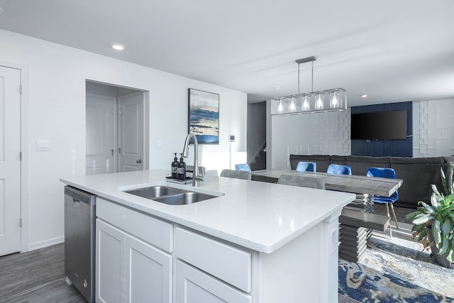 kitchen featuring decorative light fixtures, dishwasher, an island with sink, sink, and white cabinets