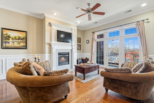 living room with ceiling fan, crown molding, and light wood-type flooring