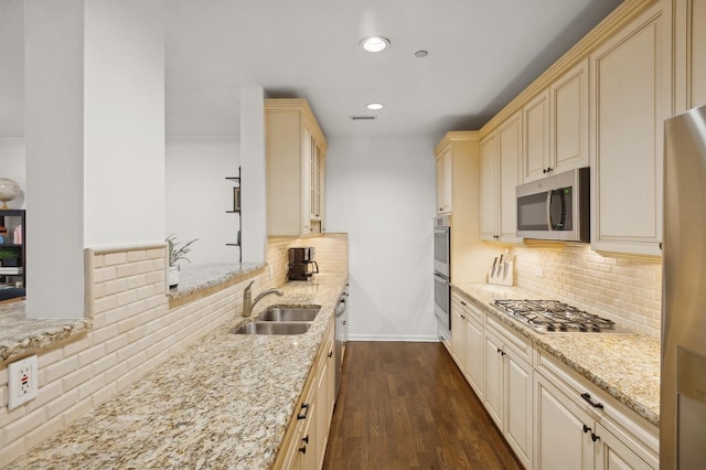 kitchen with sink, cream cabinets, stainless steel appliances, and light stone countertops