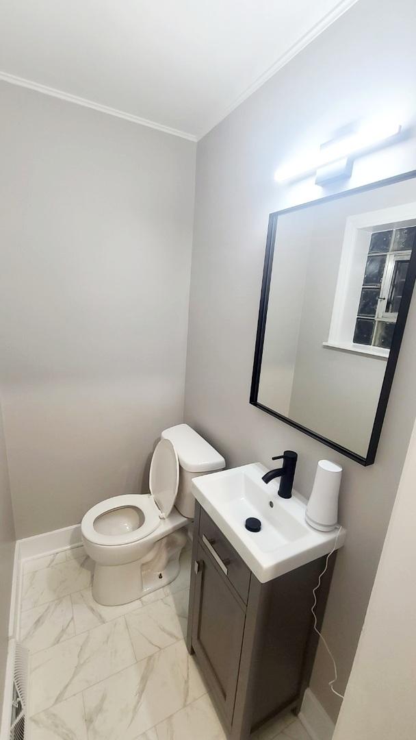 bathroom featuring toilet, ornamental molding, and vanity