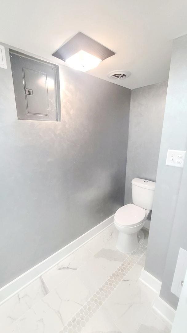 bathroom featuring electric panel and toilet