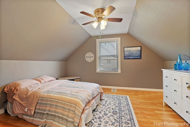 bedroom with ceiling fan, lofted ceiling, and light wood-type flooring