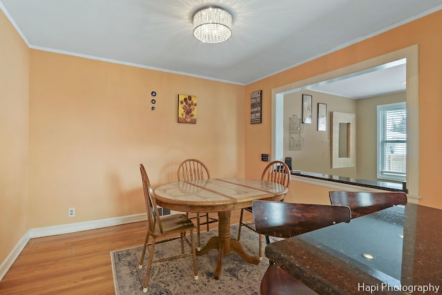 dining area with light hardwood / wood-style flooring, crown molding, and a chandelier