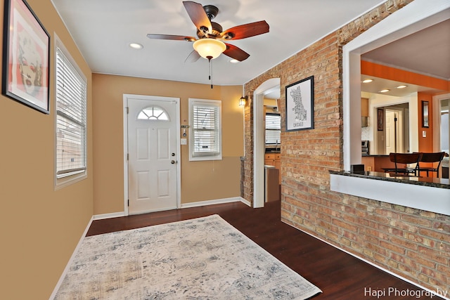 entrance foyer featuring ceiling fan, dark hardwood / wood-style floors, and brick wall