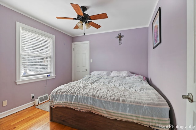 bedroom featuring ceiling fan, wood-type flooring, and crown molding