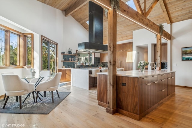 kitchen featuring ventilation hood, an island with sink, light wood-type flooring, and wood ceiling