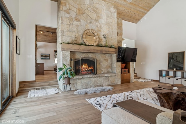 living room with a fireplace, light hardwood / wood-style flooring, high vaulted ceiling, and wooden ceiling