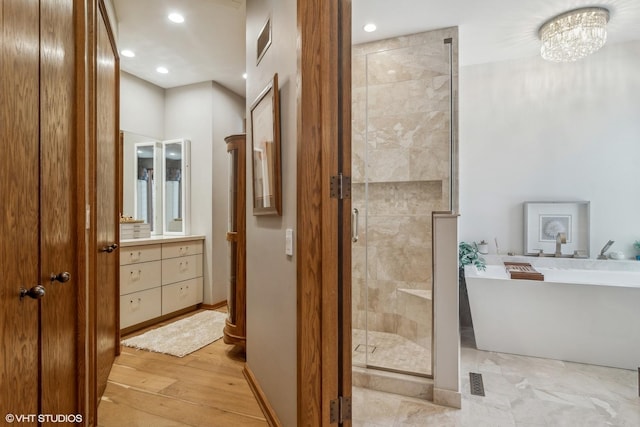 bathroom featuring vanity, wood-type flooring, separate shower and tub, and an inviting chandelier