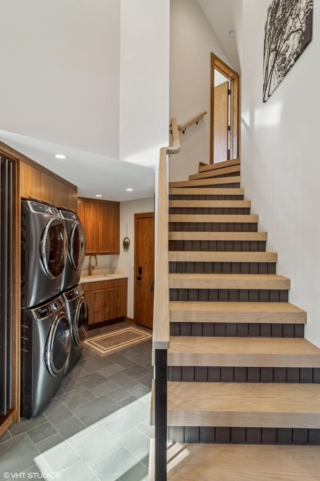 stairs with stacked washer / drying machine, sink, and a high ceiling