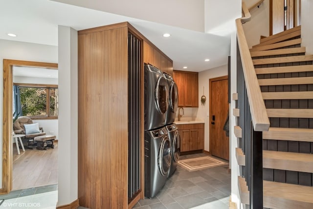 laundry area featuring cabinets, stacked washer / dryer, and sink