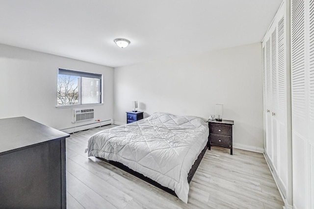 bedroom featuring a baseboard heating unit, a wall unit AC, and light hardwood / wood-style floors