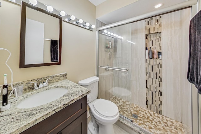 bathroom with toilet, vanity, and a shower with door