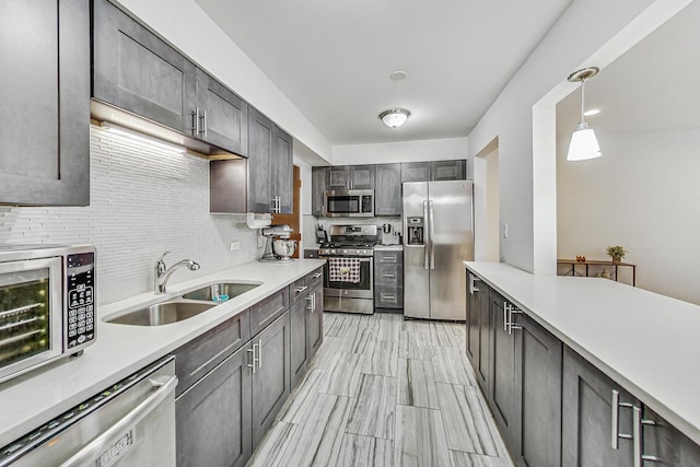 kitchen with hanging light fixtures, decorative backsplash, sink, and stainless steel appliances